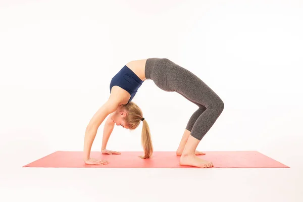 Young attractive yogi woman practicing yoga, stretching in Urdhva Dhanurasana exercise, Bridge pose, working out, wearing sportswear, blue sports bra, pants, indoor full length, isolated — Stock Photo, Image