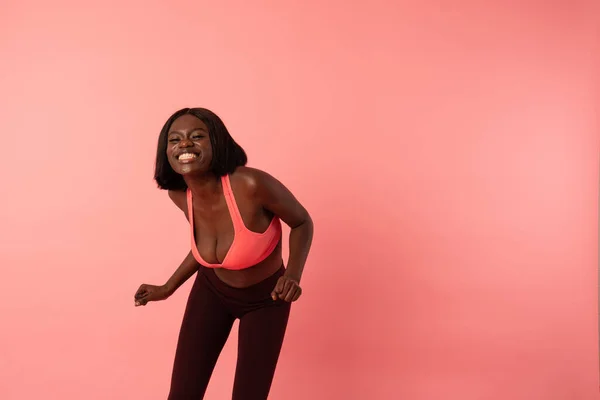 快乐而兴奋的身穿运动服的非洲女孩笑着看着摄像机，被粉色的背景隔开了 — 图库照片