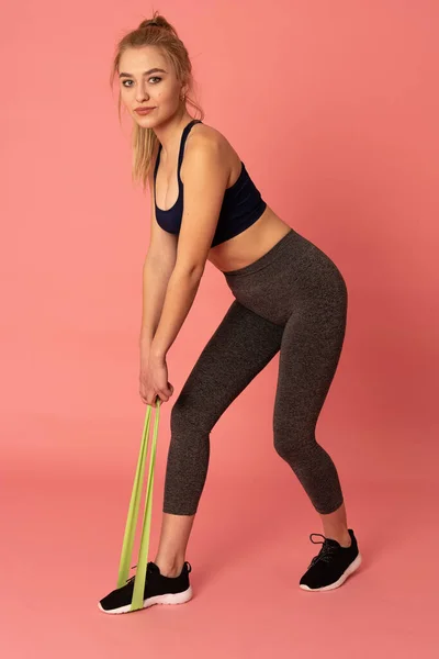 Mujer rubia atractiva haciendo ejercicio con una banda de resistencia como parte del entrenamiento de fitness —  Fotos de Stock