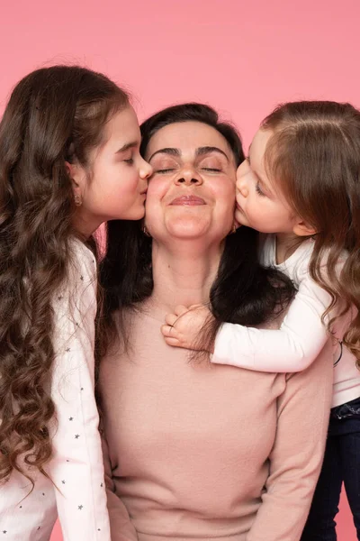 Porträtt av små döttrar som kysser sin vackra glada mor med slutna ögon — Stockfoto