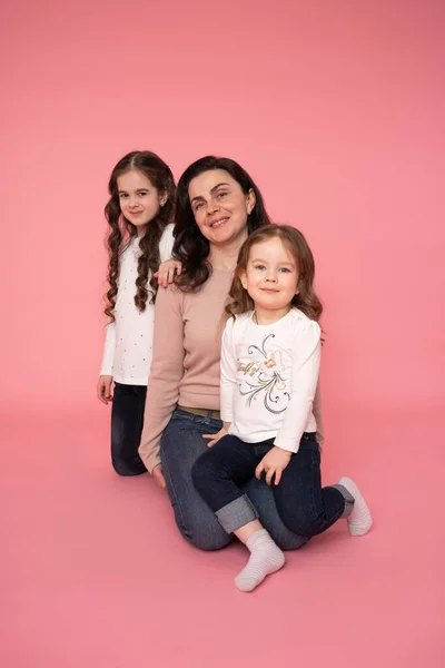 Kvinna i lätta kläder ha kul med söta barn babys flickor. Mor, små barn döttrar isolerade på pastell rosa vägg bakgrund, studio porträtt. Mors dag kärlek familj, föräldraskap barndom — Stockfoto