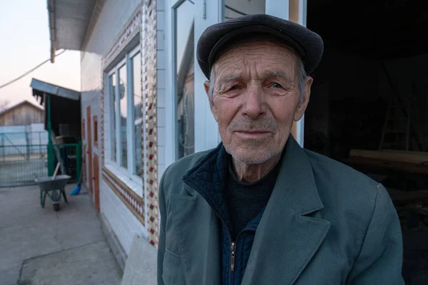 Vita foto di vecchio in giacca grigia e cappello si trova vicino alla sua casa — Foto Stock
