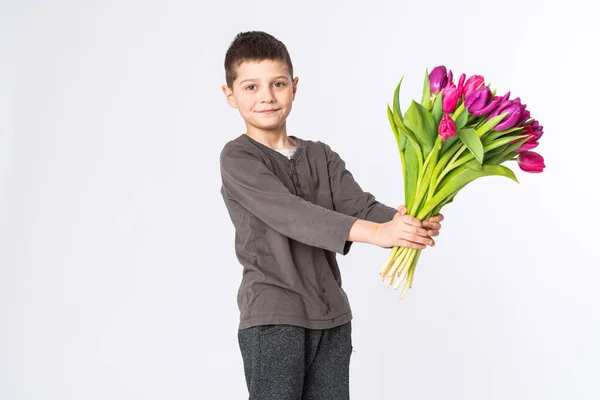 Porträtt av en leende pojke med rosa bukett tulpaner för mamma våren blommor koncept Mors dag, Alla hjärtans gåva till kvinna — Stockfoto