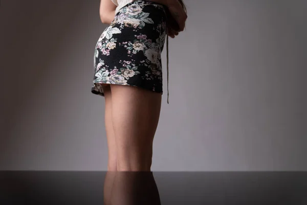 サイドビュークロップド写真の若い女性で黒のスカートに隔離された灰色の背景 — ストック写真