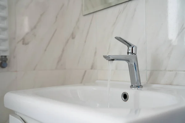 Lavabo dell'acqua del rubinetto cromato aperto in bagno. Rubinetto moderno del rubinetto cromato con uso dell'acqua corrente per lo sfondo — Foto Stock