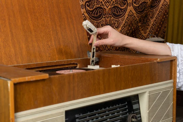 Female hand puts vinyl record in a retro radio