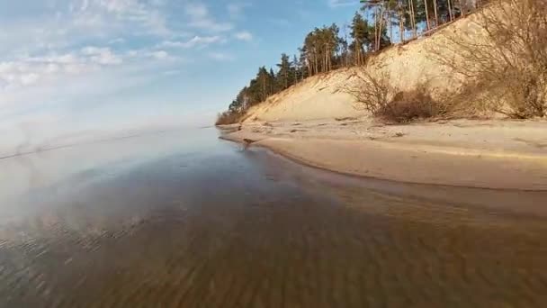Lac forestier au printemps. Forêt de conifères ensoleillée sur une autre rive et surface calme du lac avec reflet du ciel bleu avec des nuages .