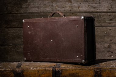 Eski çizik bavul ahşap masada duruyor.