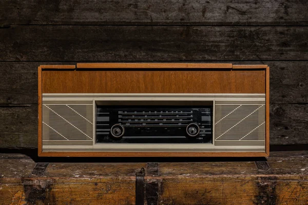 Rádio antigo fica no peito envelhecido em fundo de madeira vintage — Fotografia de Stock