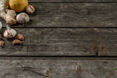 Sarımsak, limon, zencefil, ahşap bir masanın sol köşesinde soğuk algınlığına iyi gelir.