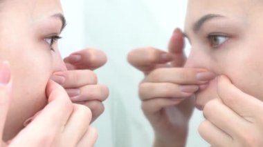 Avrupalı genç ve güzel bir kadın sivilcesini sıkıyor, sivilcesini yüzünden çıkarıyor. Kadın cilt bakımı kavramı.