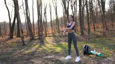 Bahar parkında esneme hareketleri yapan çekici bir bayan koşucu. Formda kız dışarıda egzersiz yapıyor. Spor antrenörü kolunu esnetiyor..