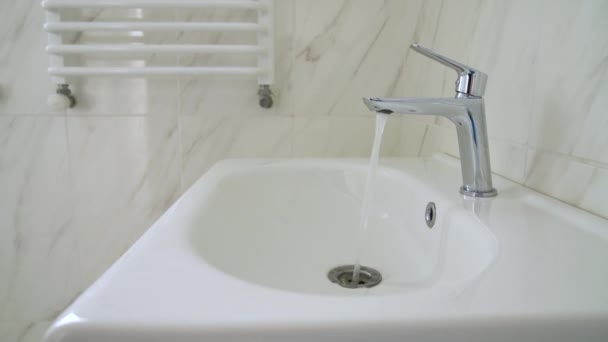 Fregadero cromado con diseño moderno en baño. El agua potable fluye de un grifo de agua cromada — Vídeo de stock