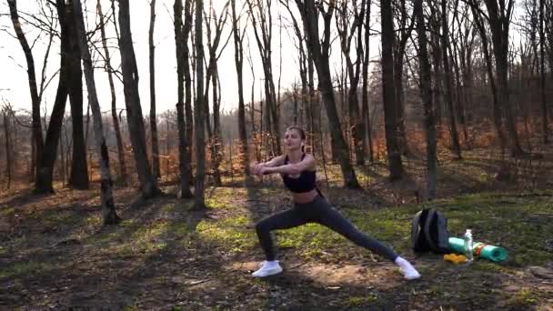 Mladá sportovní dívka s dlouhými vlasy v šedých kamaších školení v zeleném lese během jara — Stock video