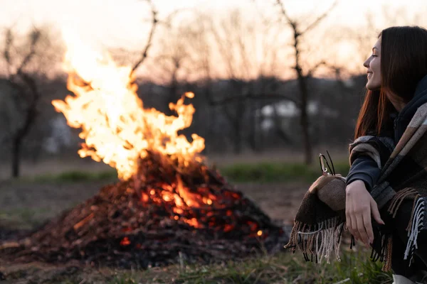 Felice giovane donna seduta vicino alla sera notte di mezza primavera falò tra i campi — Foto Stock