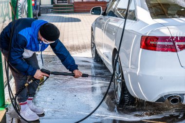 Bağlantısız oto yıkama servisi. Genç bir erkek arabasını yıkıyor.