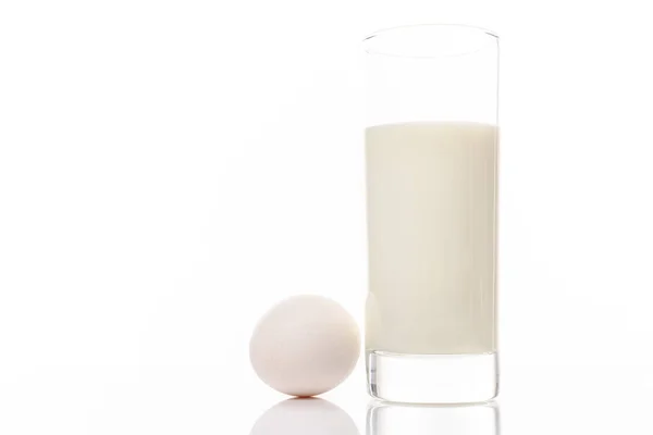 Leche ecológica en un vaso y huevo de pollo blanco aislado sobre fondo blanco —  Fotos de Stock