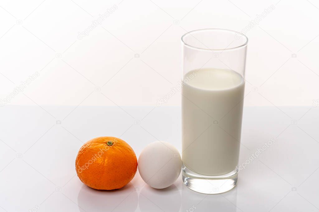 Healthy nutrition. Fresh mandarin, organic egg and a glass of milk isolated on white background