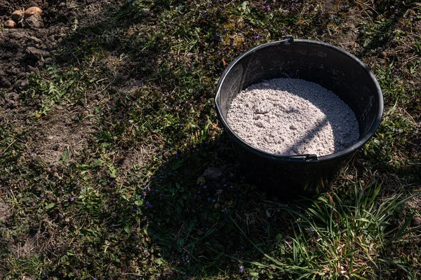 The black plastic bucket with a granulated fertilizer — Stock Photo, Image