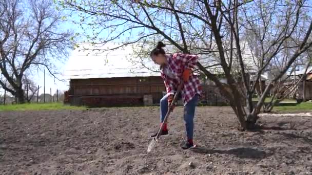 Vrouwelijke tuinman in geruit shirt graven in de tuin met schoppen — Stockvideo