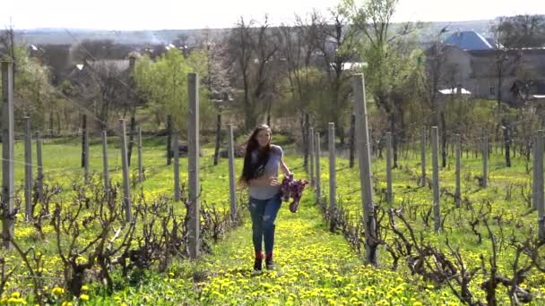 Веселая улыбающаяся девушка с брюнеткой длинными волосами бежит к камере вдоль виноградника — стоковое видео