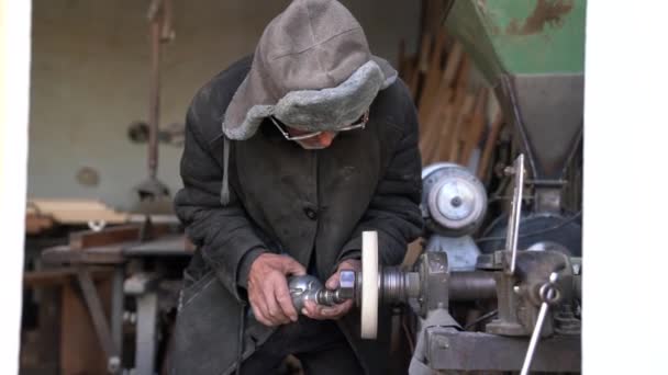 안경을 쓴 노인은 분쇄기로 드릴을 날카롭게 닦는다 — 비디오