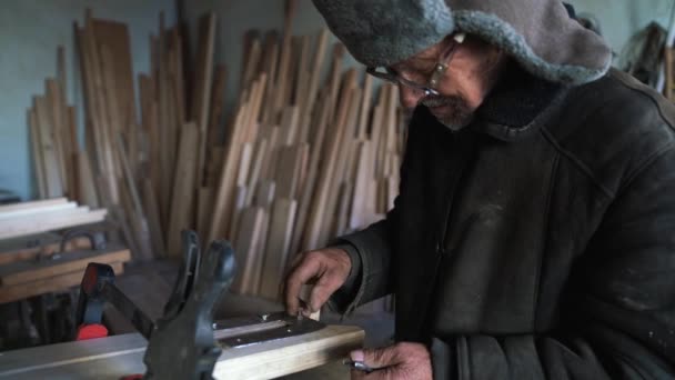 Carpenter in glasses fastens metal plank to the wooden stepladder with screw — Stock Video