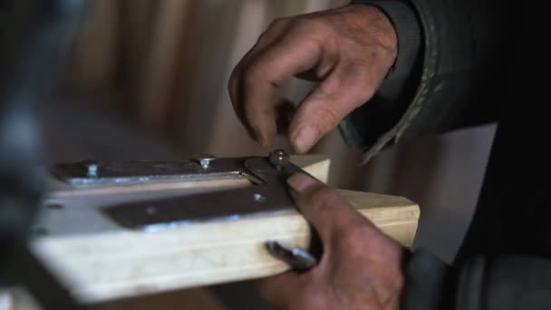 Verouderde mannelijke handen schroeven de moer van metalen plank op de houten trapladder los — Stockvideo