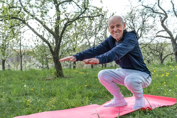 Nonno pensionato. Allenamento sportivo attivo per anziani. Concetto di sport e pensione. Uomo anziano esercizio su stuoia di yoga rosa . — Foto Stock