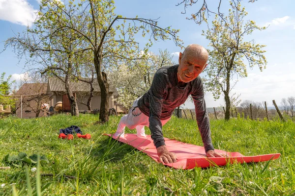 Matita anziana in piedi a tavola. Home sport allenamento statico. Stile di vita di quarantena a distanza sociale. Assistenza sanitaria. Persona yoga asana. Ashtanga posa. Allungamento muscolare . — Foto Stock