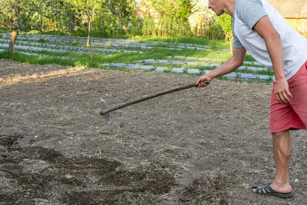 Casual male works with hoe in the garden at home — Stock Photo, Image