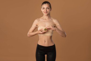 Bej sütyenli mutlu esmer kız elinde altın Bitcoin ile kameraya bakıyor.