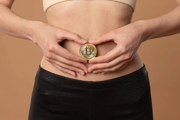 一位年轻女性的近照，她双手托着比特币金币女孩的腹部 — 图库照片