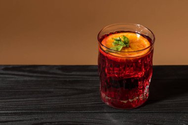 Kanı tazeleyen portakal kırmızısı su veya ahşap bir masanın üzerindeki bardakta eritilmiş su.