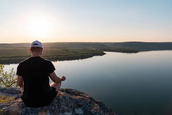 Sağlıklı yoga meditasyon konsepti. Genç adam, tropikal nehrin altındaki kayanın üzerinde lotus pozisyonunda kameraya doğru oturuyor. — Stok fotoğraf