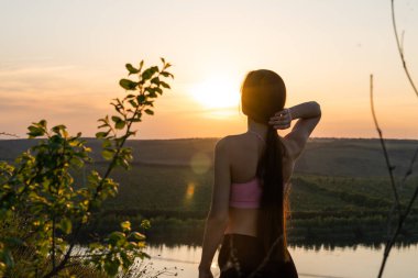 Kaygısız esmer kadın gün doğumuyla birlikte dağ yamacının tepesinde doğa otlağının tadını çıkarıyor. Güzellik Kızı Açık Hava