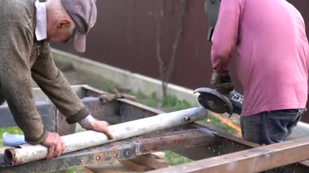 Twee mannelijke arbeiders snijden metalen platen met elektrische rooster in de werkplaats — Stockvideo