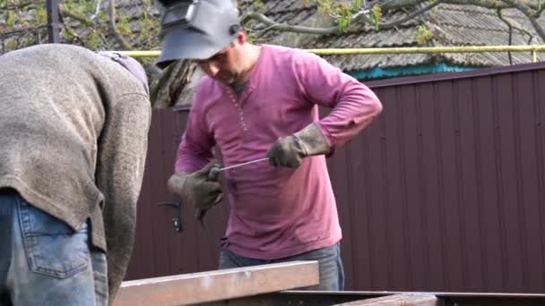 Dois machos prepaerd para o dia de trabalho, homem em camisa vermelha e máscara protativa insere um electrde — Vídeo de Stock