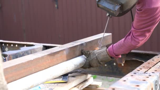 Un giovane saldatore saldare metallo con una saldatrice ad arco presso il cantiere — Video Stock