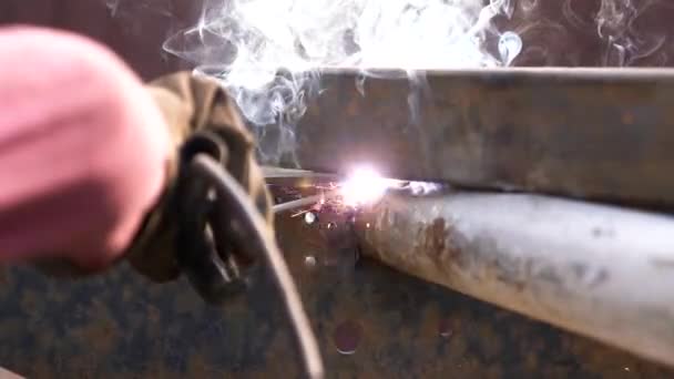 Svářečka v ochranné uniformě svařování kovové trubky na průmyslovém stole, zatímco jiskry létání — Stock video