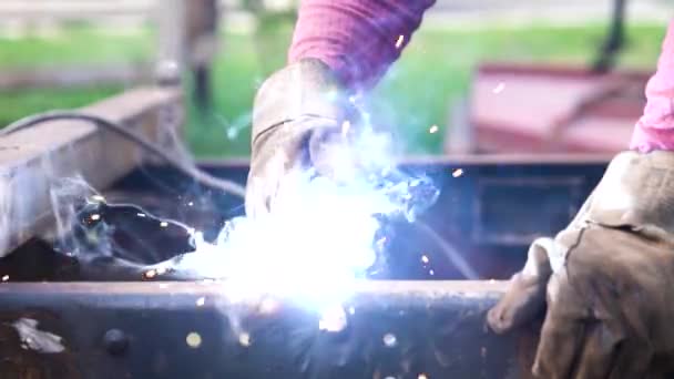 Close-up portretweergave van professioneel beschermde lasser in uniform werkend aan de metalen sculptuur aan tafel in het industriële weefsel — Stockvideo