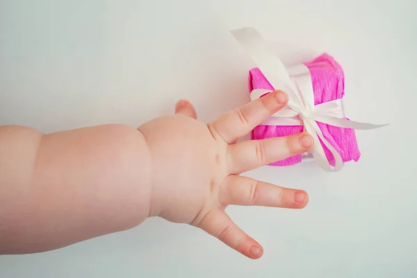 Детская рука тянется за красивой подарочной коробкой на белой спине Лицензионные Стоковые Фото