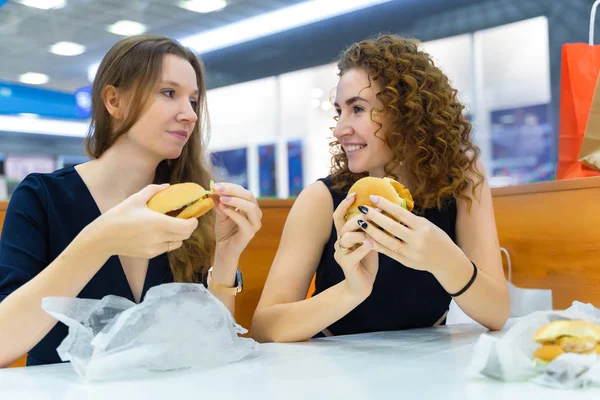 Duas meninas sexy bonitas estão sentadas a uma mesa em um café em um s — Fotografia de Stock