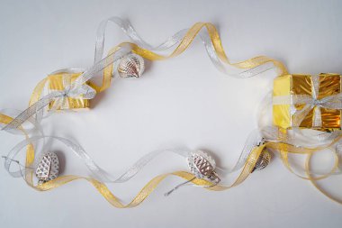 Parlak altın ve gümüş kurdeleler ve Noel oyuncakları beyaz bir şeyin üzerinde yatıyor. 