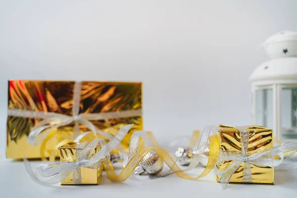 Λαμπερές χρυσές και ασημένιες κορδέλες και χριστουγεννιάτικα παιχνίδια βρίσκονται σε ένα λευκό — Φωτογραφία Αρχείου