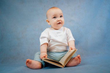 Hafif giysili şirin küçük çocuk tuhaf bir şekilde yaprakları karıştırıyor. 