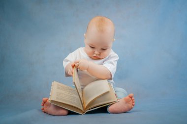 Hafif giysili şirin küçük çocuk tuhaf bir şekilde yaprakları karıştırıyor. 
