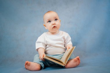 Hafif giysili şirin küçük çocuk tuhaf bir şekilde yaprakları karıştırıyor. 