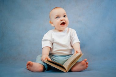 Hafif giysili şirin küçük çocuk tuhaf bir şekilde yaprakları karıştırıyor. 