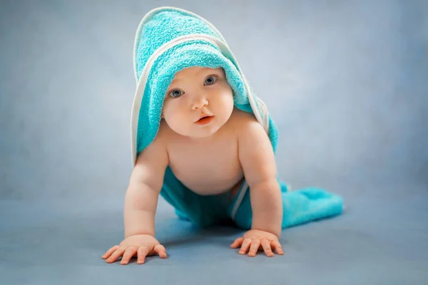 Aranyos kisbaba mászik fürdés után egy kék törülközőben Jogdíjmentes Stock Képek